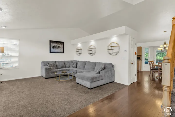 Vaulted ceilings, built-in recessed wall shelving with integrated lighting, wood-finish flooring, and a decorative staircase railing