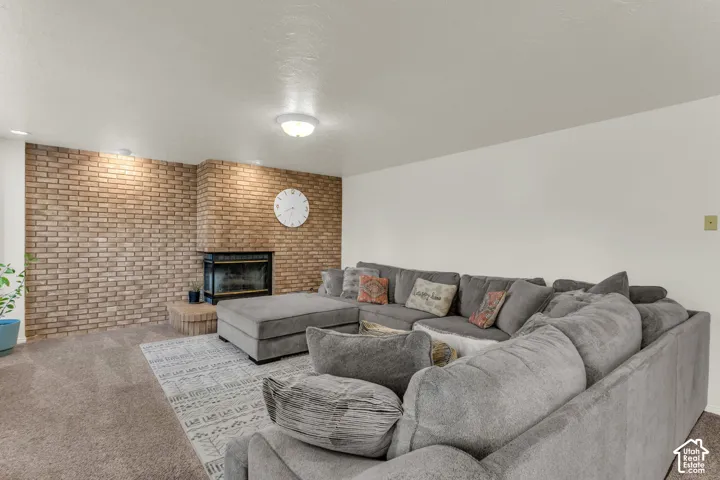 Full-wall textured brick accent, fireplace with raised brick hearth, and wall-mounted overhead lighting