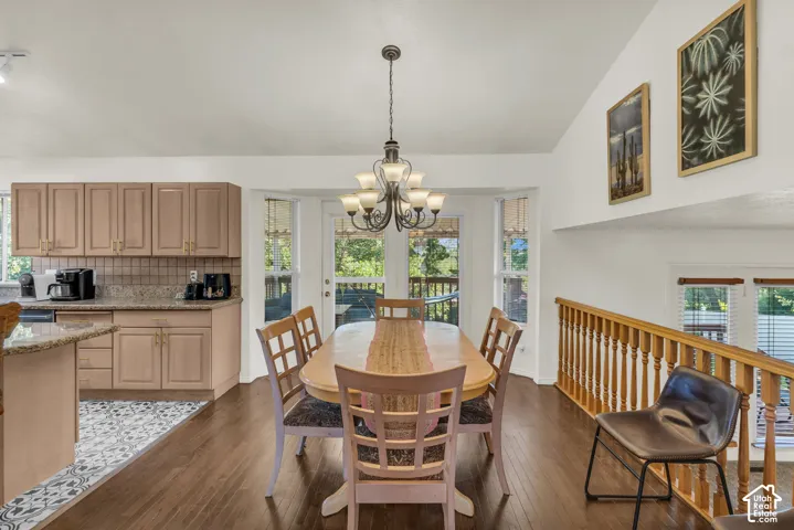 Kitchen and dining area featuring wood-finish flooring, vaulted ceilings, a multi-light chandelier, and stone-finish countertops