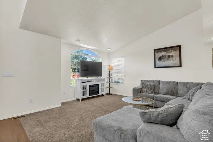 Vaulted ceiling, neutral wall tones, arched window, and recessed lighting