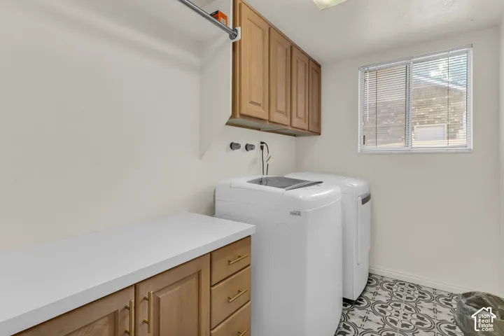 Laundry area featuring wood-finish cabinetry, a solid surface countertop, patterned tile flooring, and a wall-mounted hanging rod