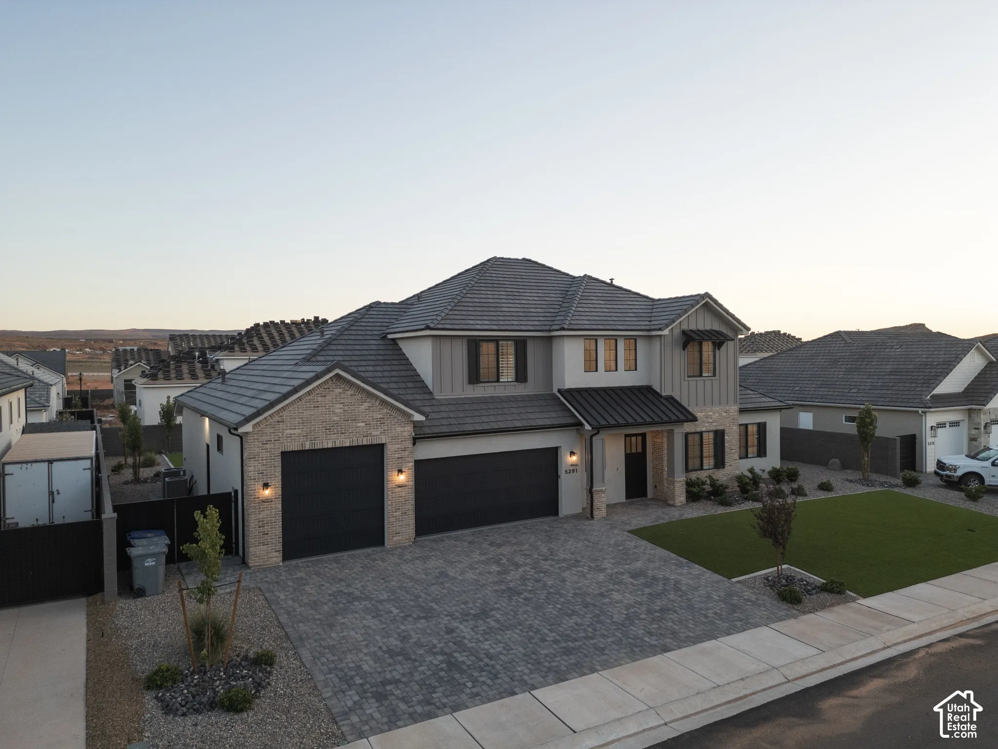 Exterior featuring a multi-gabled roofline, stone veneer and vertical siding facade, three-car garage, and paved driveway