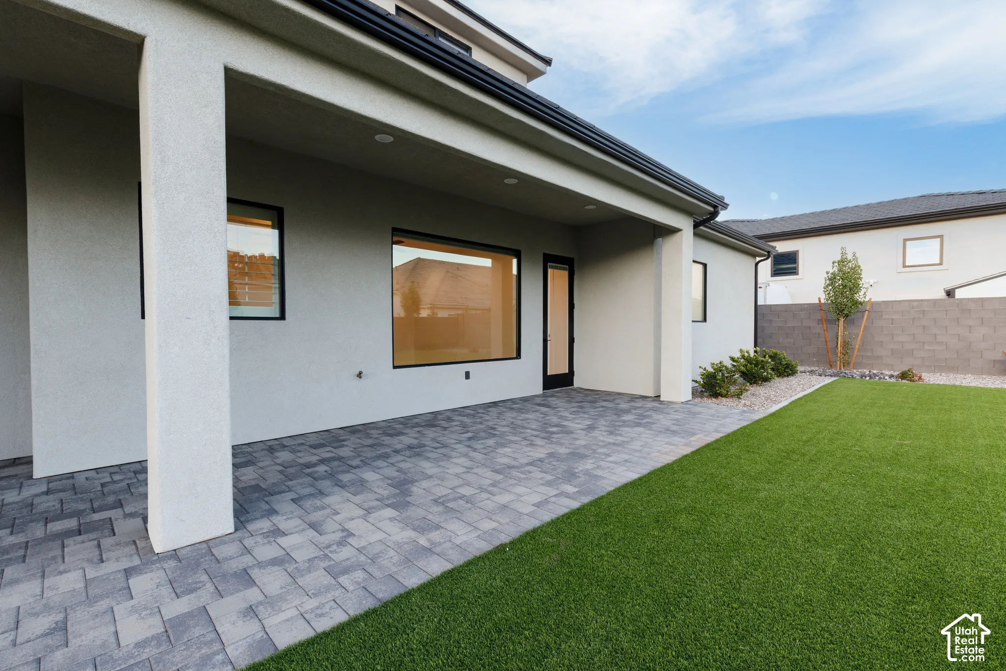 Covered patio with paver flooring, low-maintenance synthetic turf, and concrete masonry perimeter wall