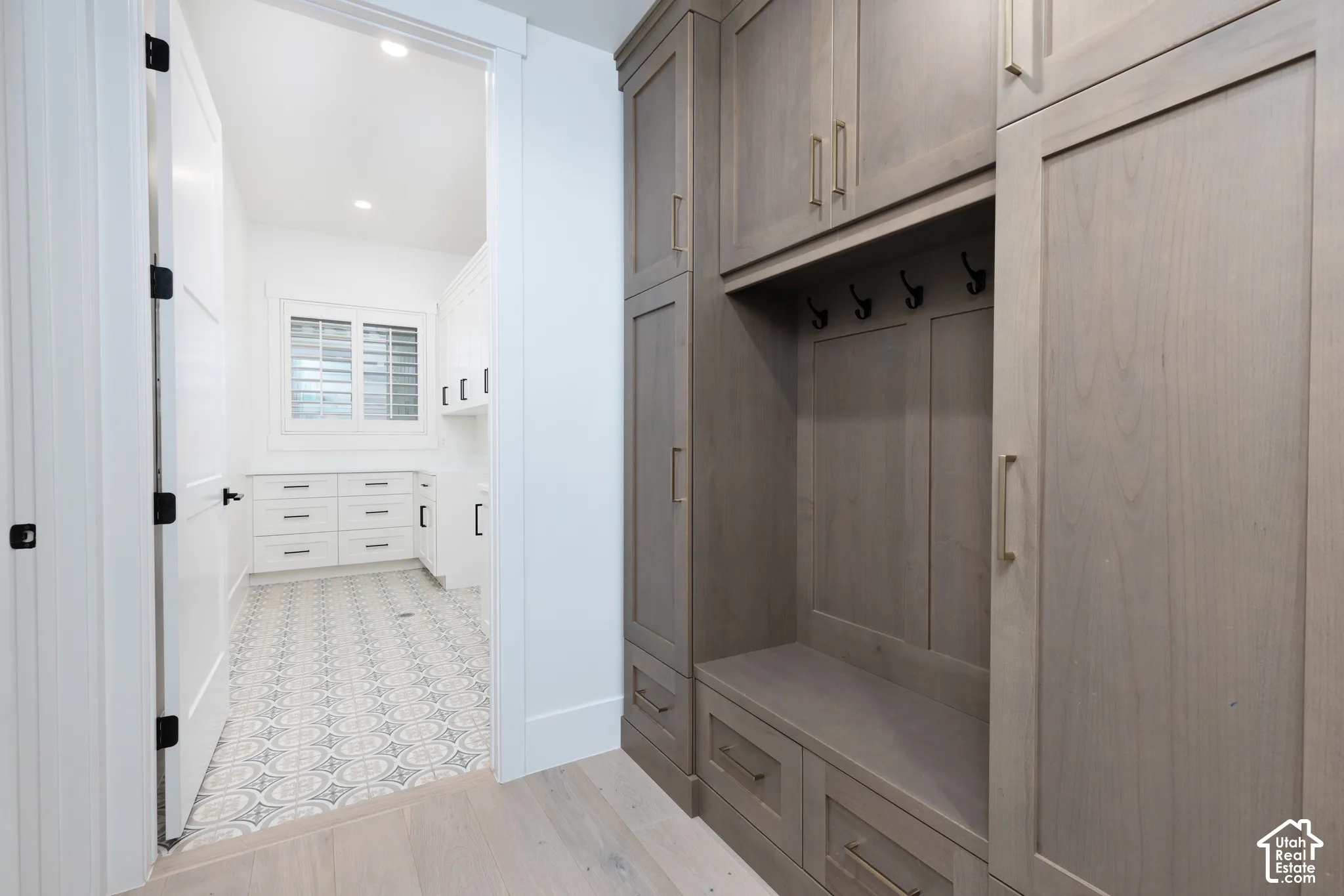 Custom floor-to-ceiling cabinetry with integrated storage bench and matte-finish hardware, paired with light-toned wood-finish flooring