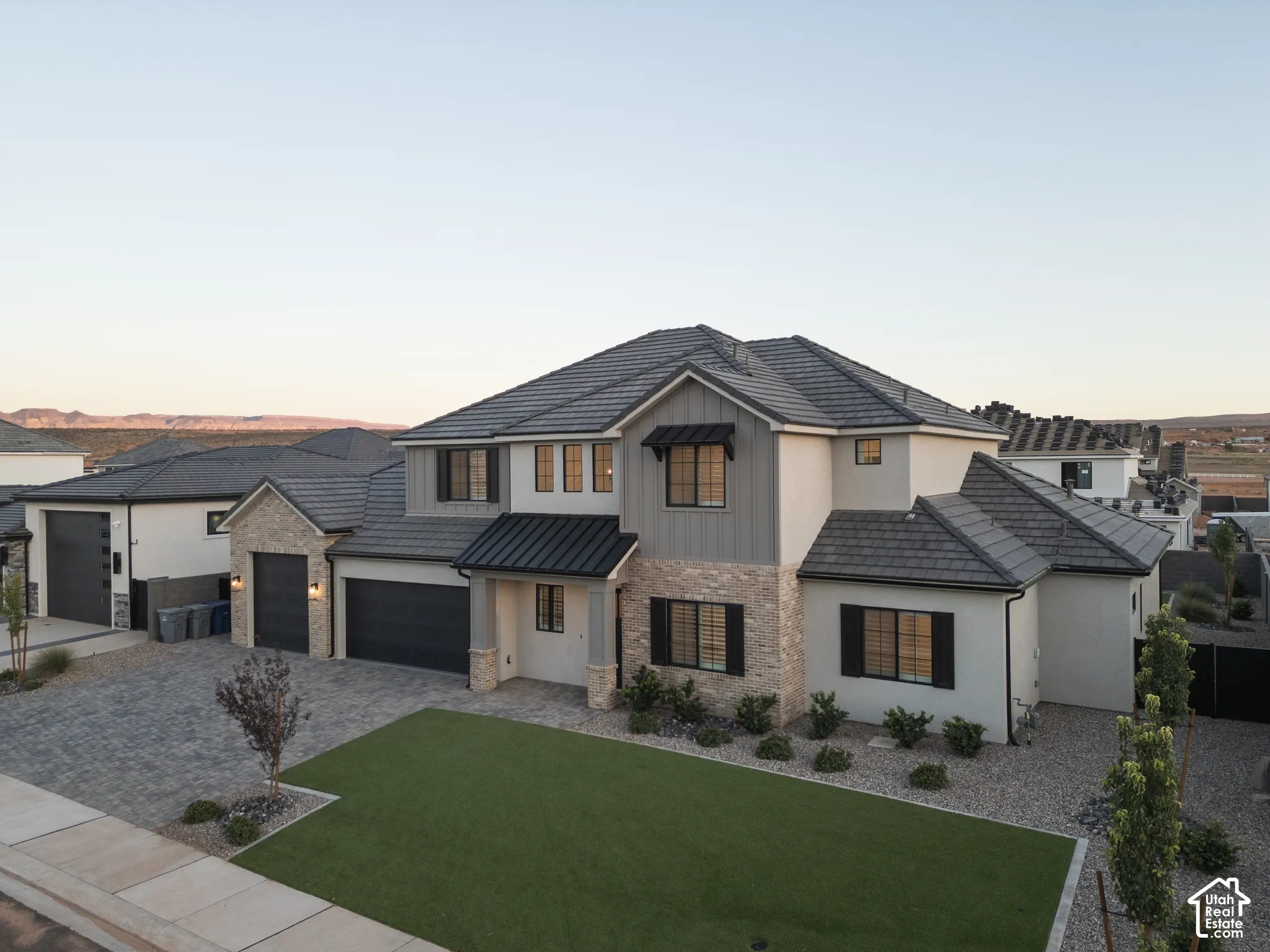 Exterior featuring a multi-gabled roofline, stone veneer accents, vertical siding, an attached three-car garage, and a paved driveway