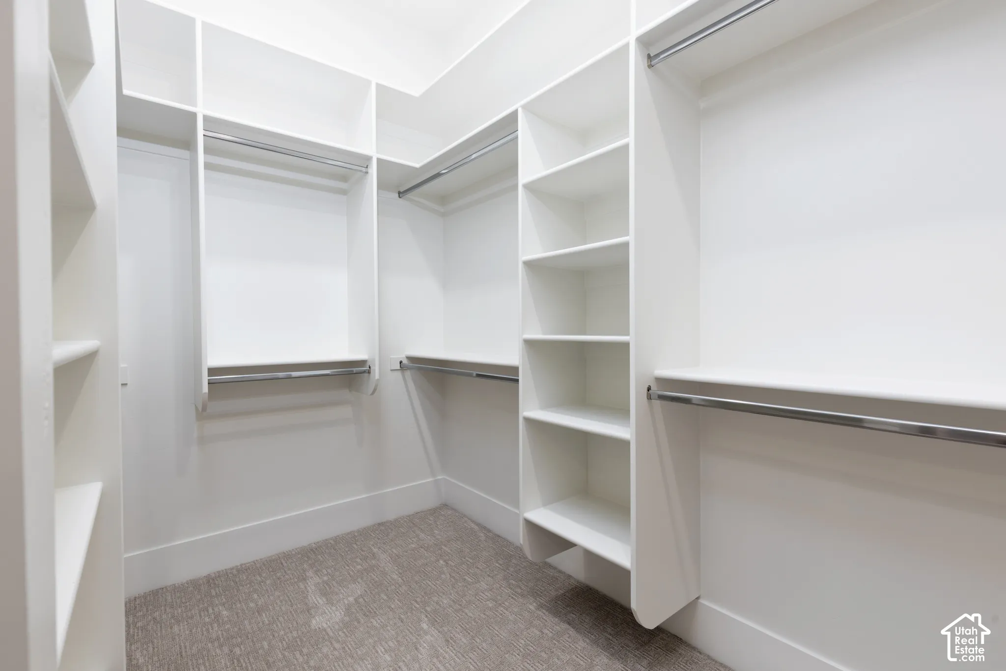 Custom white built-in shelving, multi-level hanging rods, and neutral carpeting