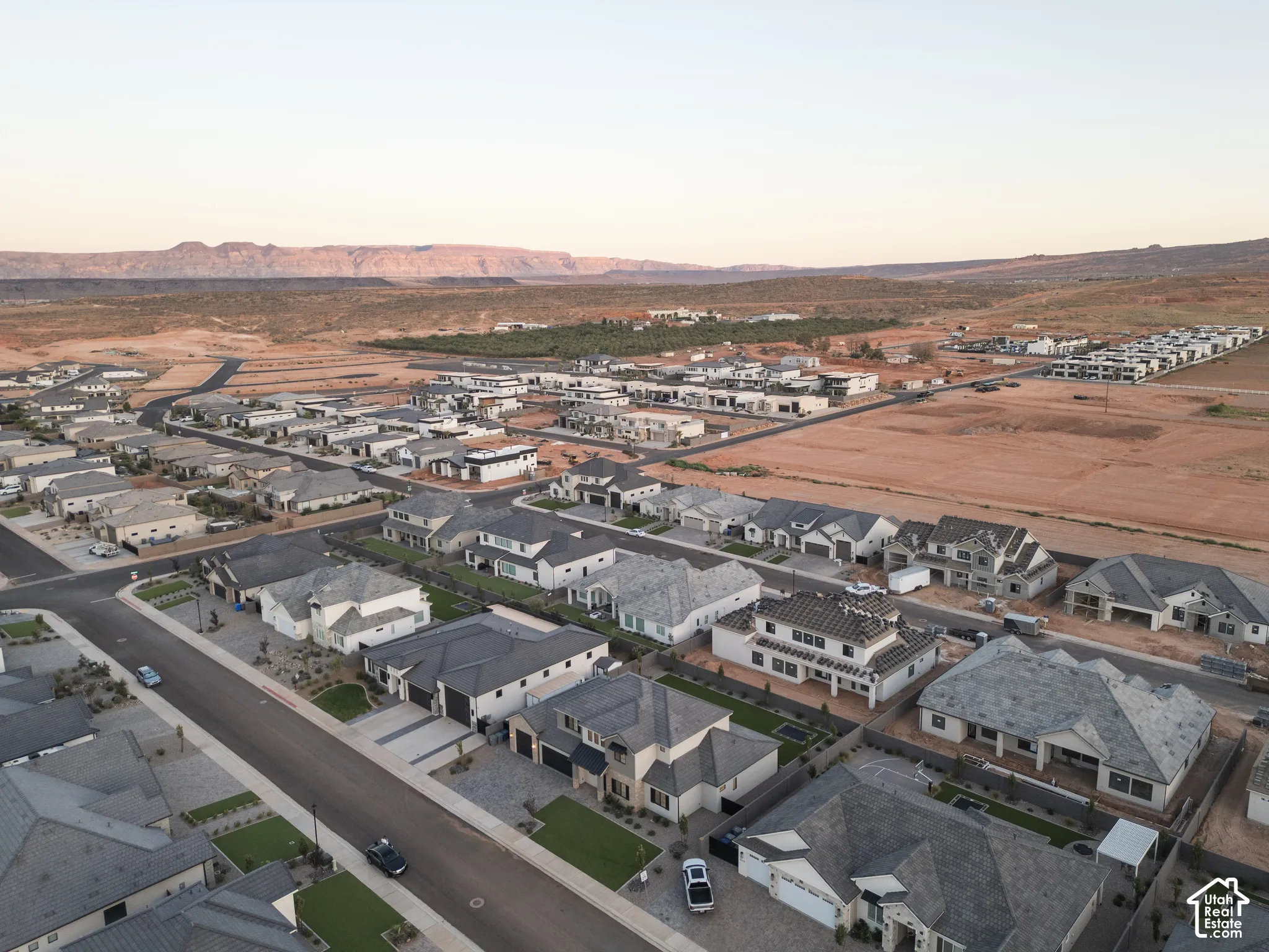 Aerial perspective of a planned community featuring paved roads, uniform residential architecture, and prominent mountainous scenery