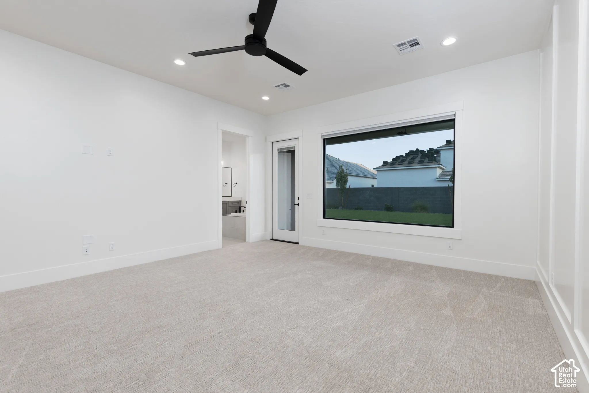 Neutral interior featuring carpeting, matte black ceiling fan, recessed lighting, expansive picture window, and board and batten wall detailing