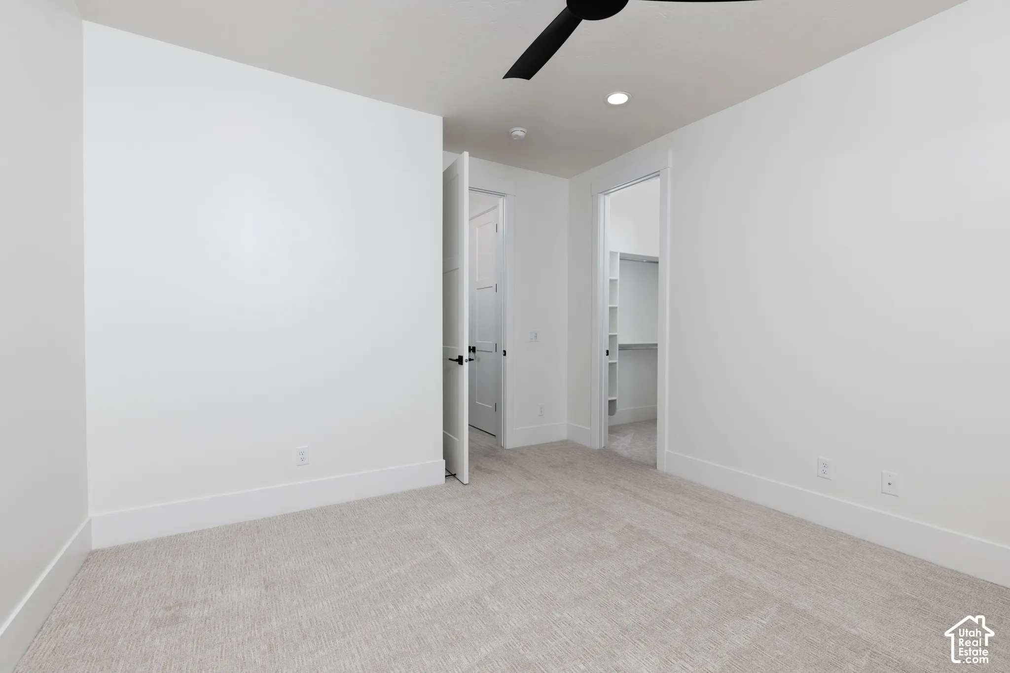 Neutral-toned carpeting, matte black ceiling fan, recessed lighting, and walk-in closet with built-in shelving