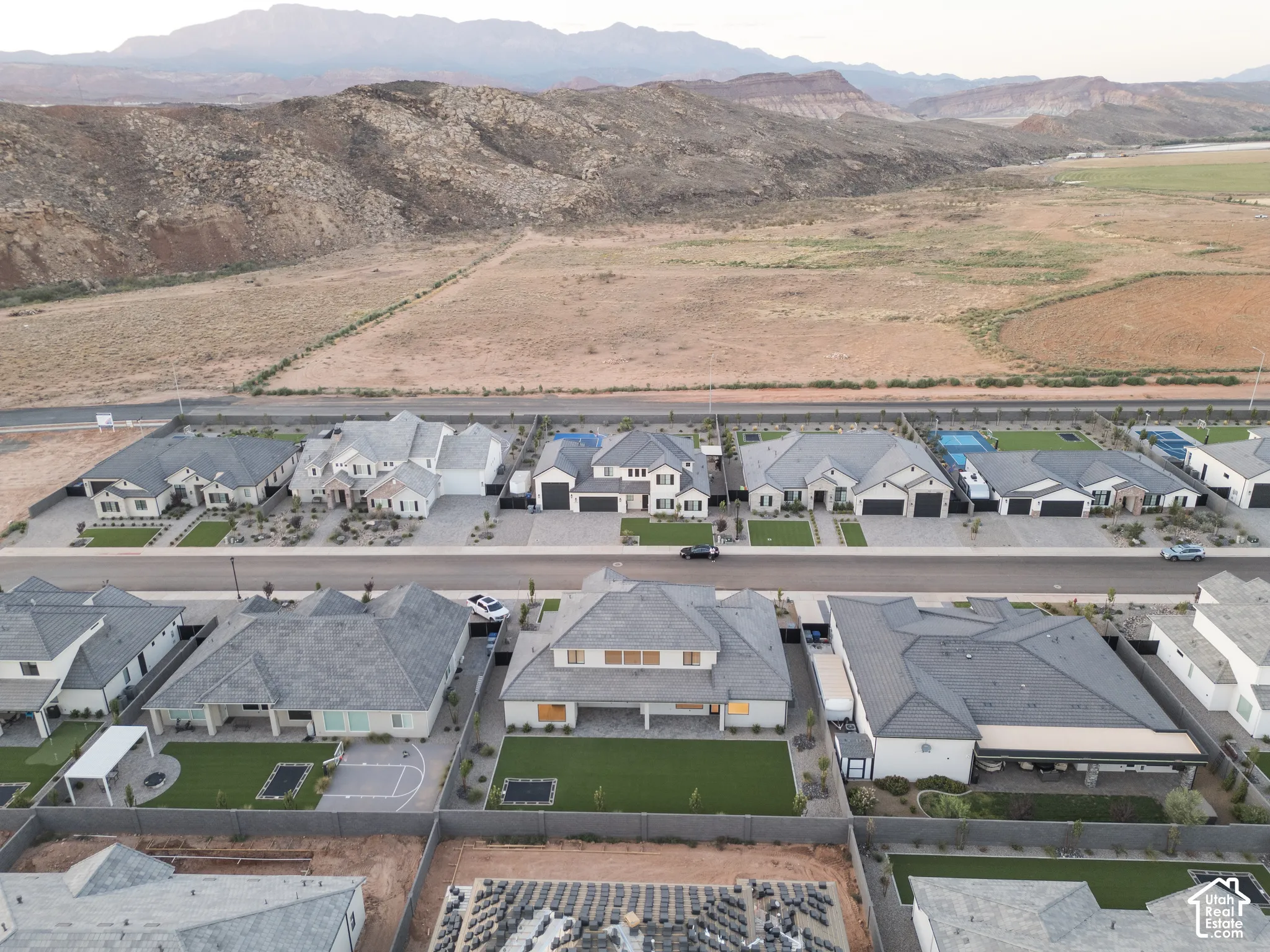 Aerial perspective featuring residential lots with manicured lawns, paved driveways, and mountain scenery