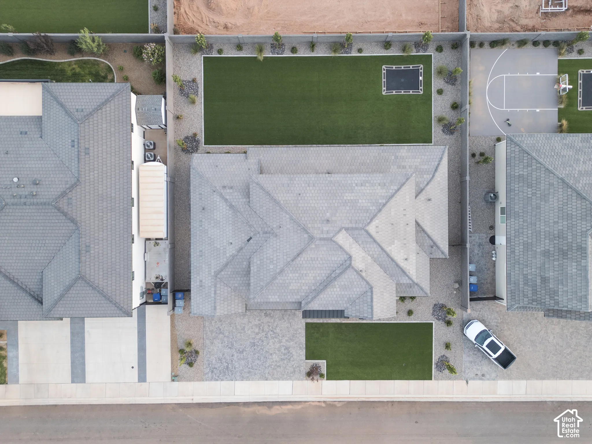 Aerial perspective featuring a tile roof, low-maintenance gravel landscaping, paved driveway, and a fenced rear yard with turf