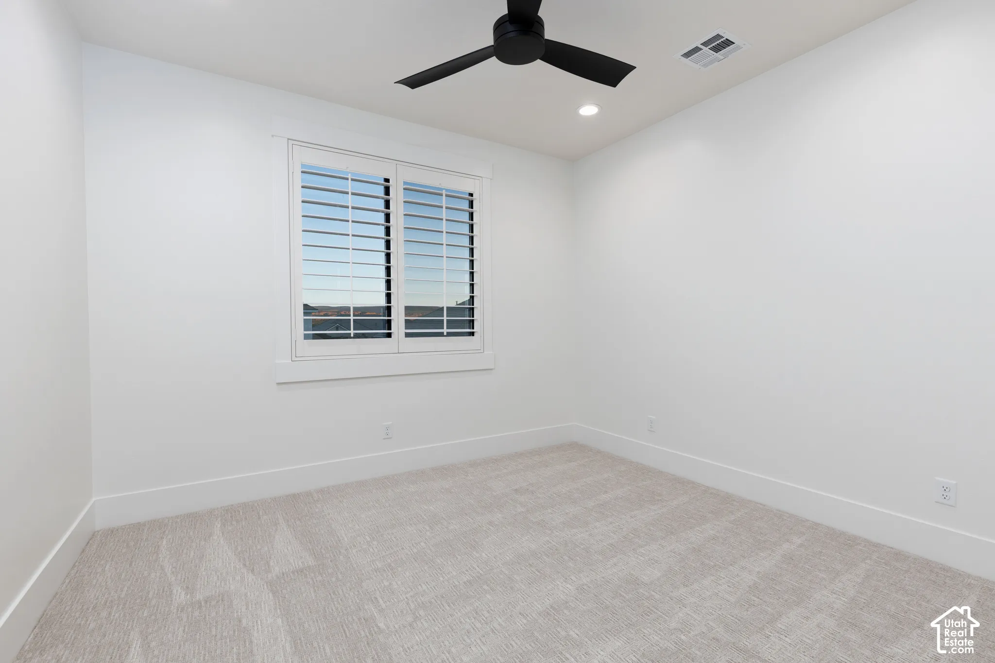 Neutral-toned wall-to-wall carpeting, matte black ceiling fan, recessed lighting, and white window shutters with thick casing