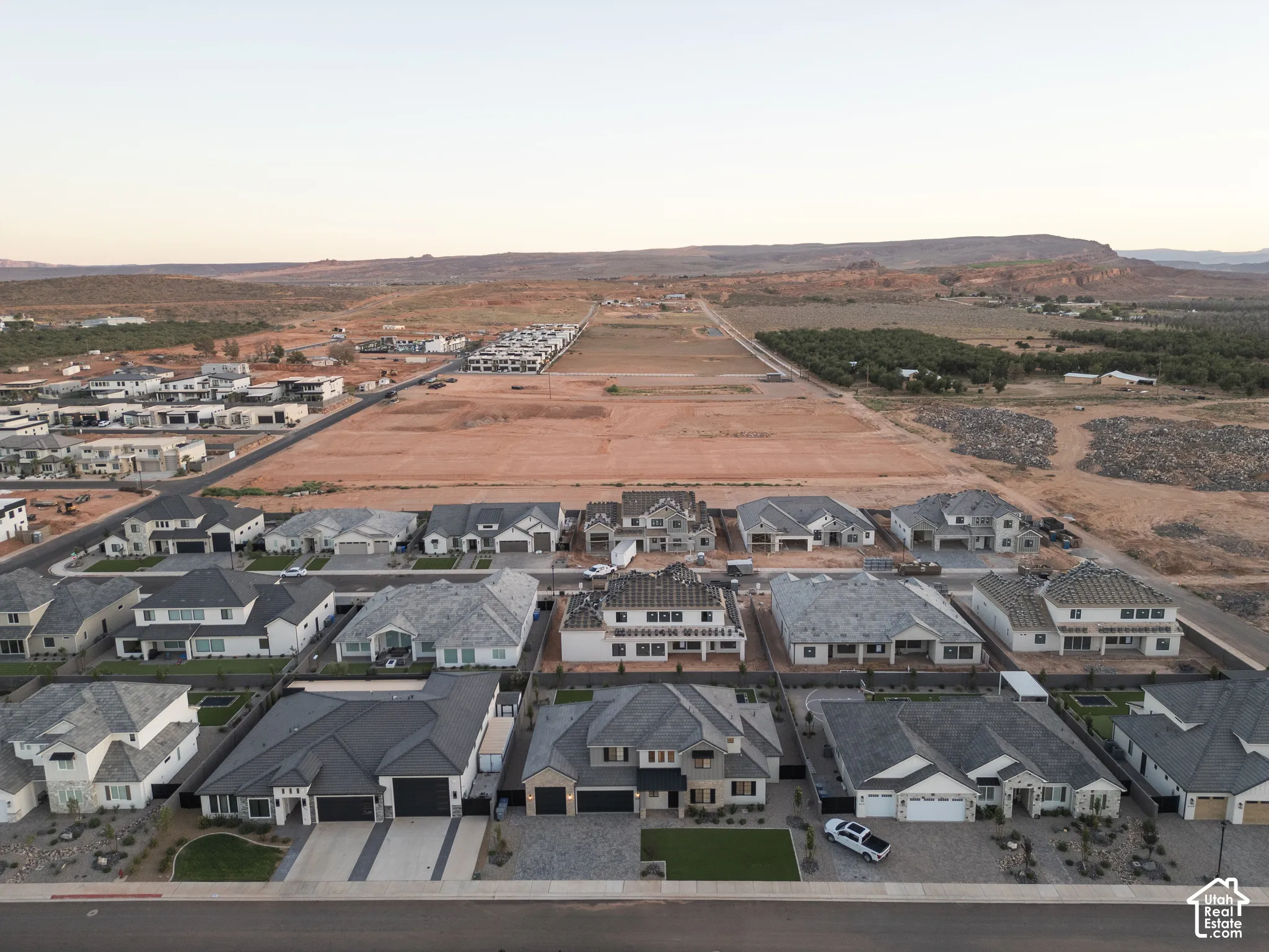 Aerial perspective of a master-planned community featuring asphalt streets, concrete driveways, xeriscaped front yards, and mountain backdrop
