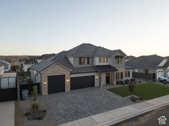 Exterior featuring a multi-gabled roofline, stone veneer and vertical siding facade, three-car garage, and paved driveway