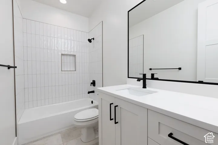 Bathroom featuring a white vanity with quartz countertop, matte black fixtures, vertical subway tile tub surround with built-in niche, and a framed vanity mirror