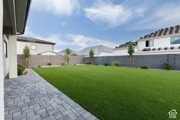 Private backyard featuring synthetic turf, concrete paver patio, and perimeter masonry block wall