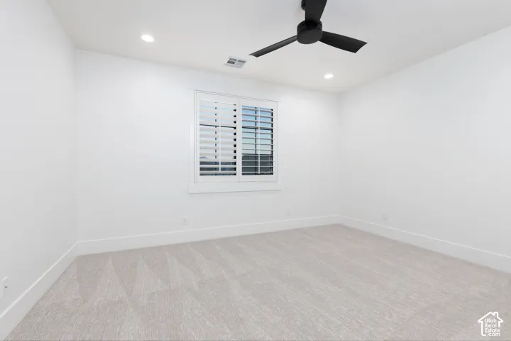 Neutral-toned carpeting, matte black ceiling fan, recessed lighting, and white plantation shutters