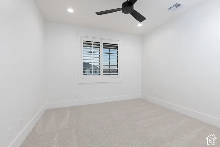 Neutral-toned carpeting, matte black ceiling fan, recessed lighting, and white plantation shutters