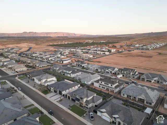 Aerial perspective of a planned community featuring paved roads, uniform residential architecture, and prominent mountainous scenery