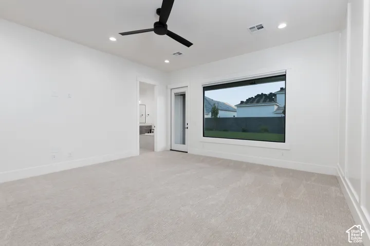 Neutral interior featuring carpeting, matte black ceiling fan, recessed lighting, expansive picture window, and board and batten wall detailing