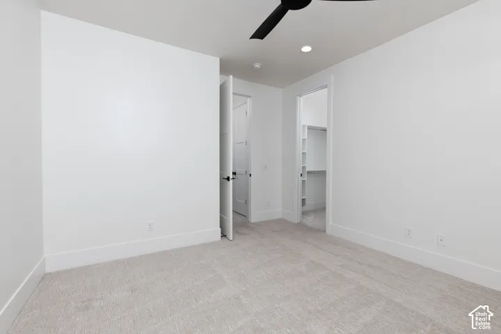 Neutral-toned carpeting, matte black ceiling fan, recessed lighting, and walk-in closet with built-in shelving