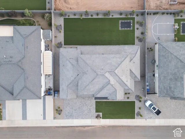 Aerial perspective featuring a tile roof, low-maintenance gravel landscaping, paved driveway, and a fenced rear yard with turf