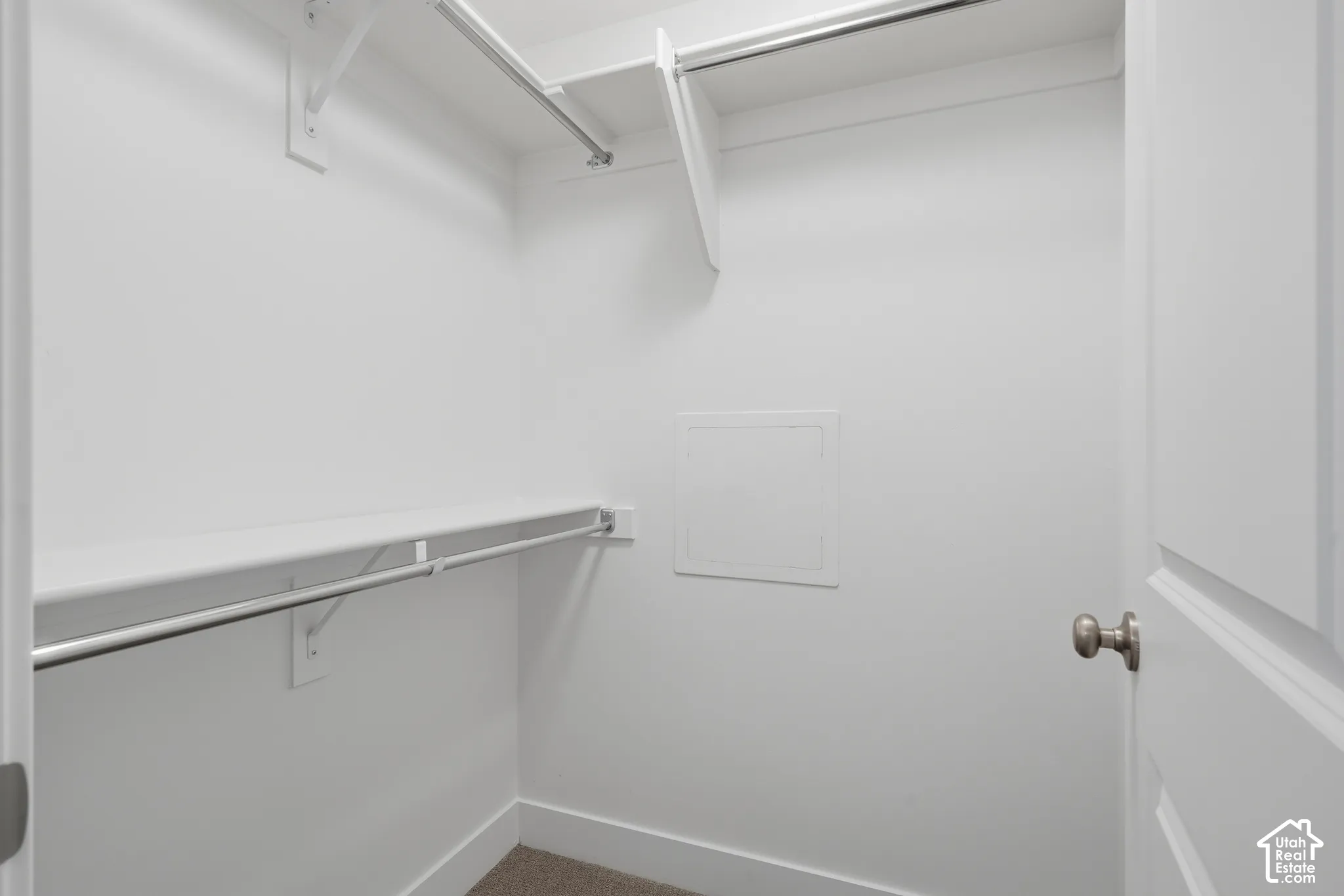Walk-in closet featuring dual-level metal hanging rods and white built-in shelving