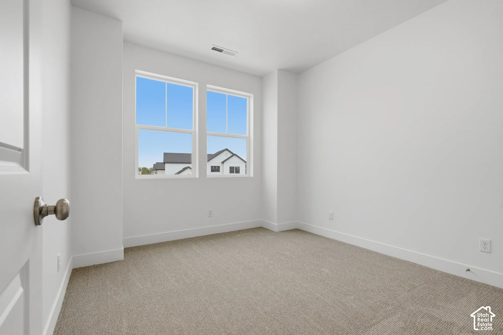 Interior space featuring neutral wall-to-wall carpeting, dual-pane windows with muntins, and crisp white wall finishes