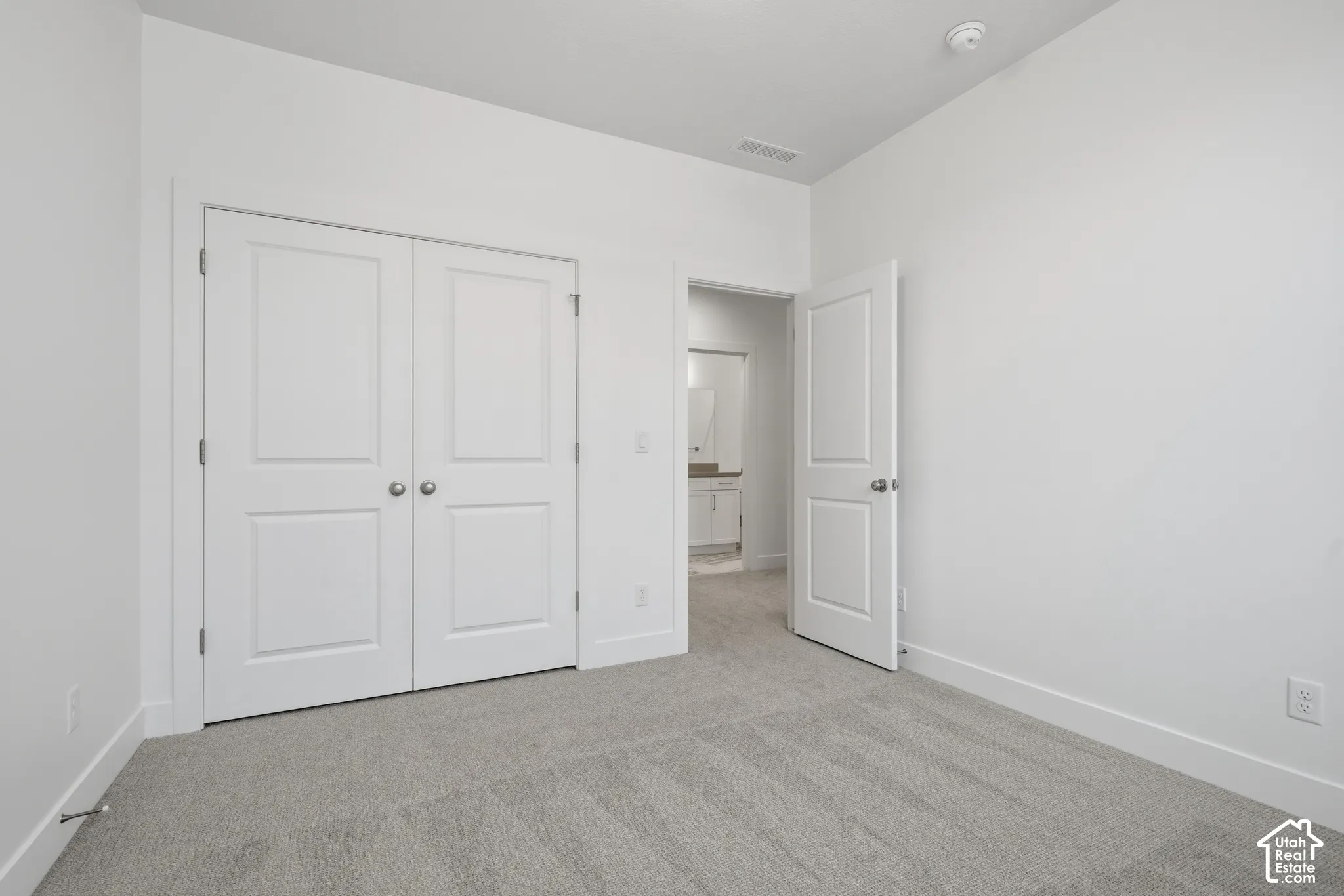 Neutral interior space featuring high ceilings, light-toned wall-to-wall carpeting, two-panel interior doors, and a double-door closet