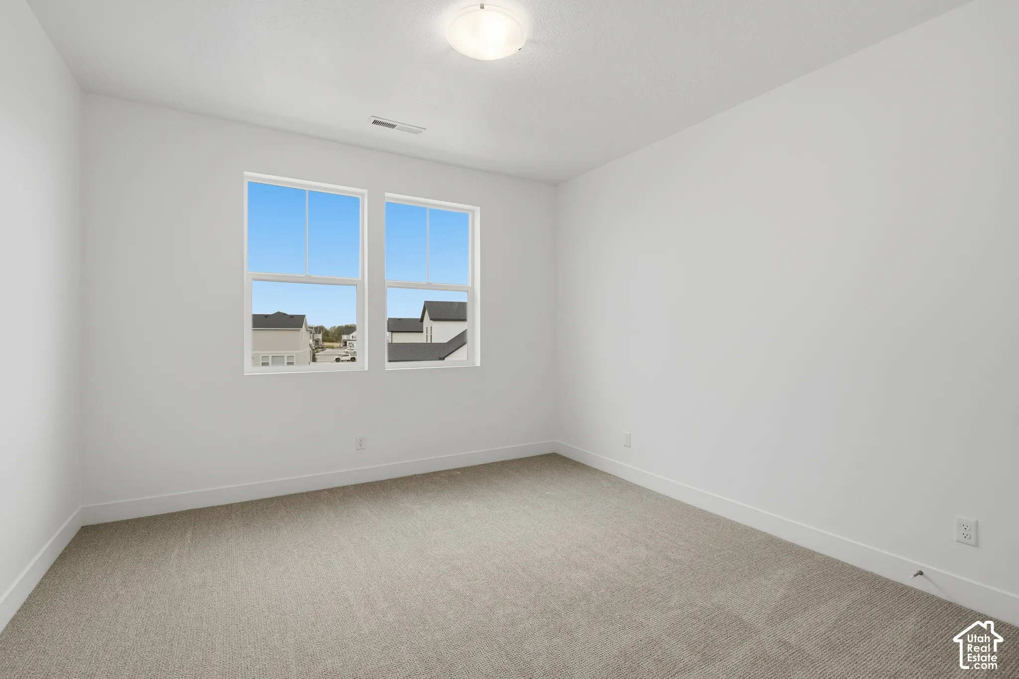 Neutral-toned wall-to-wall carpeting, dual-pane windows, and a flush-mount overhead light fixture