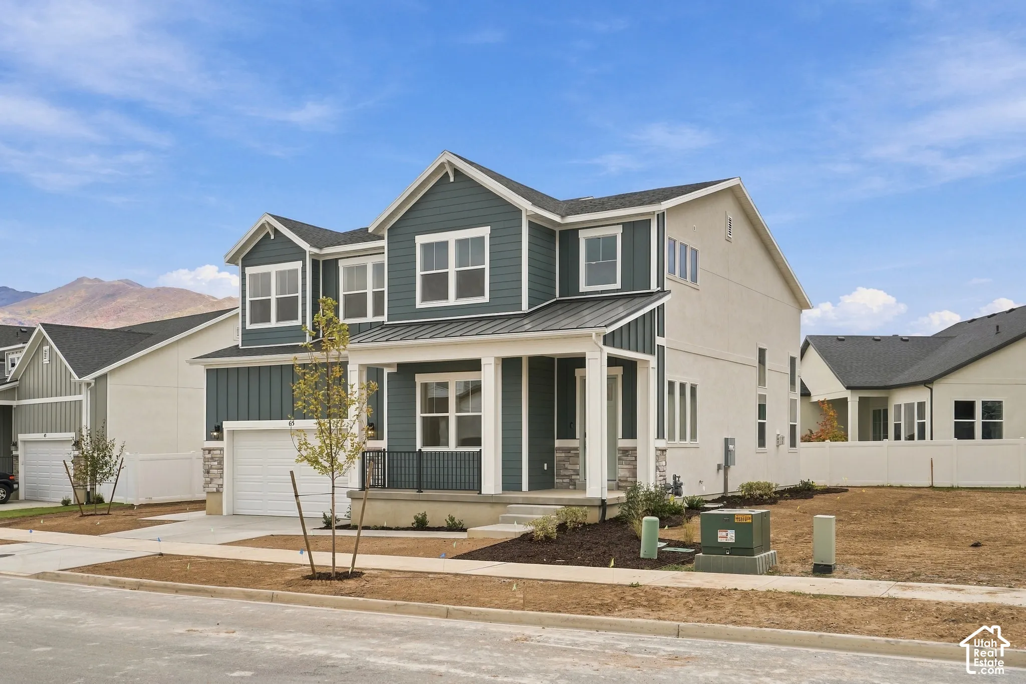 Two-story exterior featuring board-and-batten siding, stone masonry accents, a metal porch roof, and a mountain backdrop