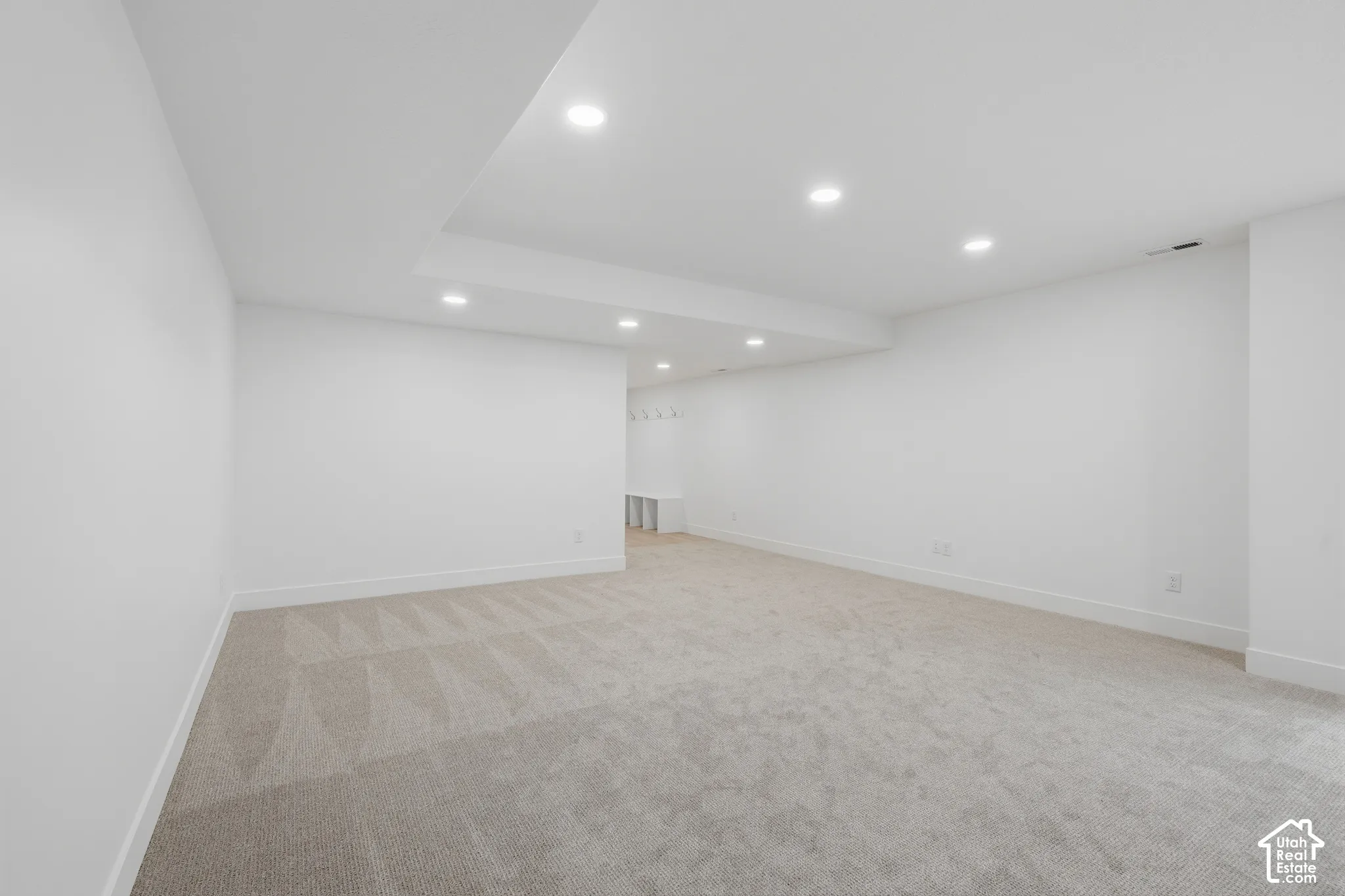Neutral interior featuring a dropped tray ceiling, recessed lighting, wall-to-wall carpeting, and built-in storage bench with wall-mounted hooks