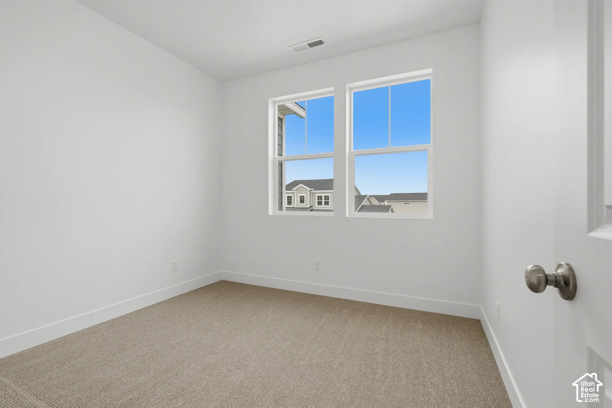 Neutral-toned wall-to-wall carpeting, dual-pane windows, and a brushed nickel door handle