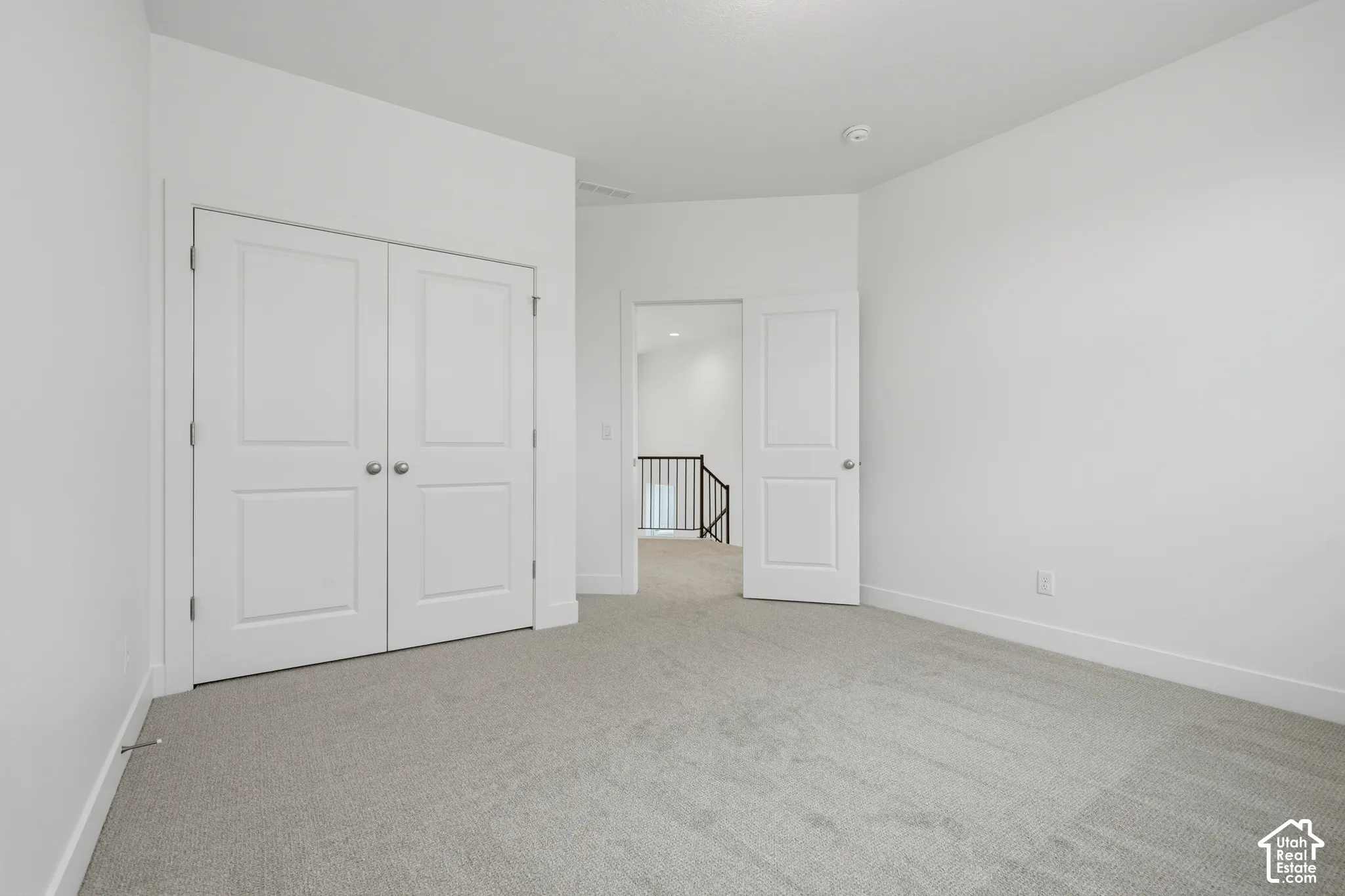 Neutral-toned carpeting, white walls, dual-panel closet doors, and solid-core passage door