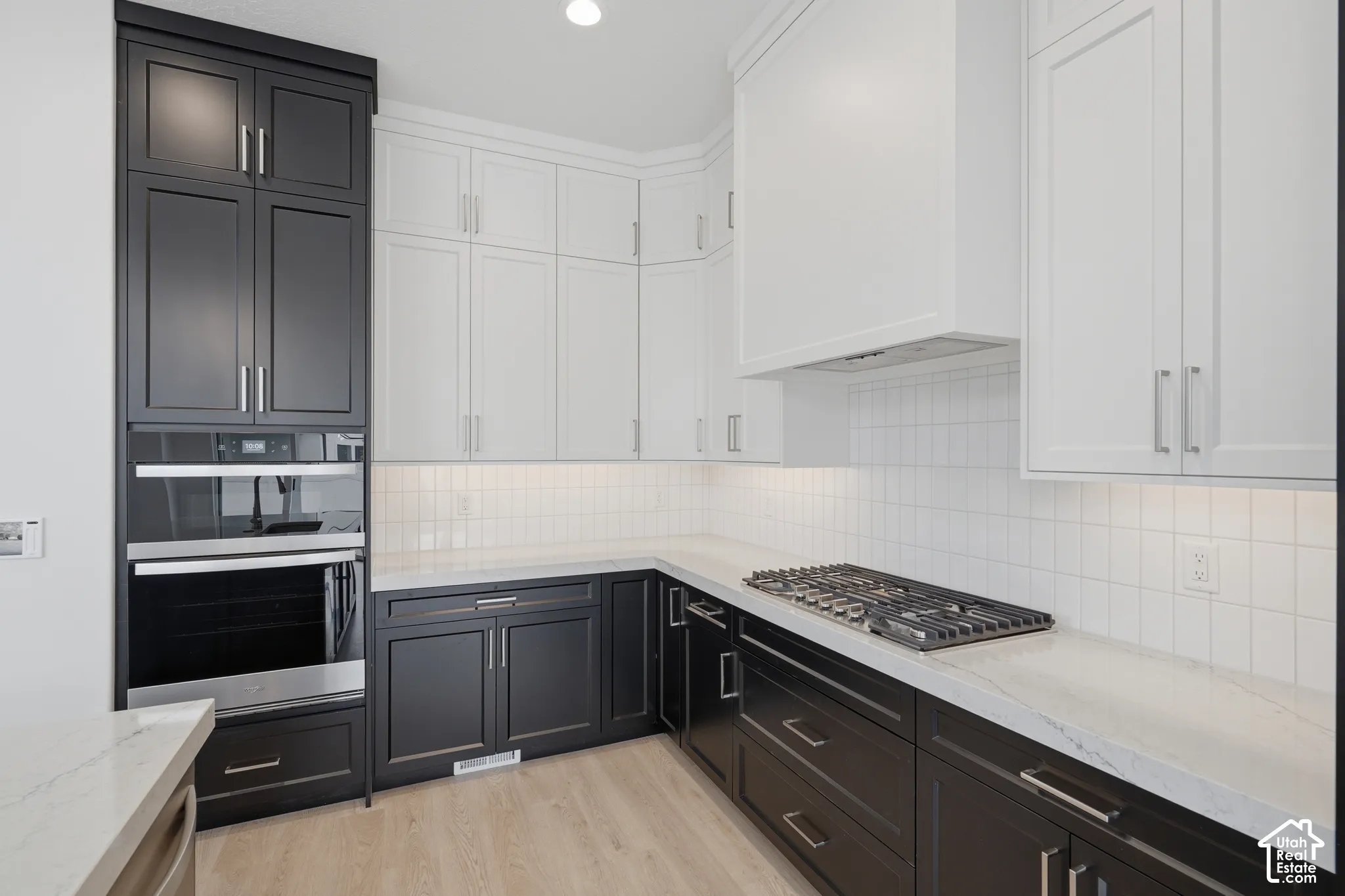 Kitchen featuring two-tone shaker-style cabinetry, quartz countertops, white tile backsplash, stainless steel built-in double oven, and gas cooktop