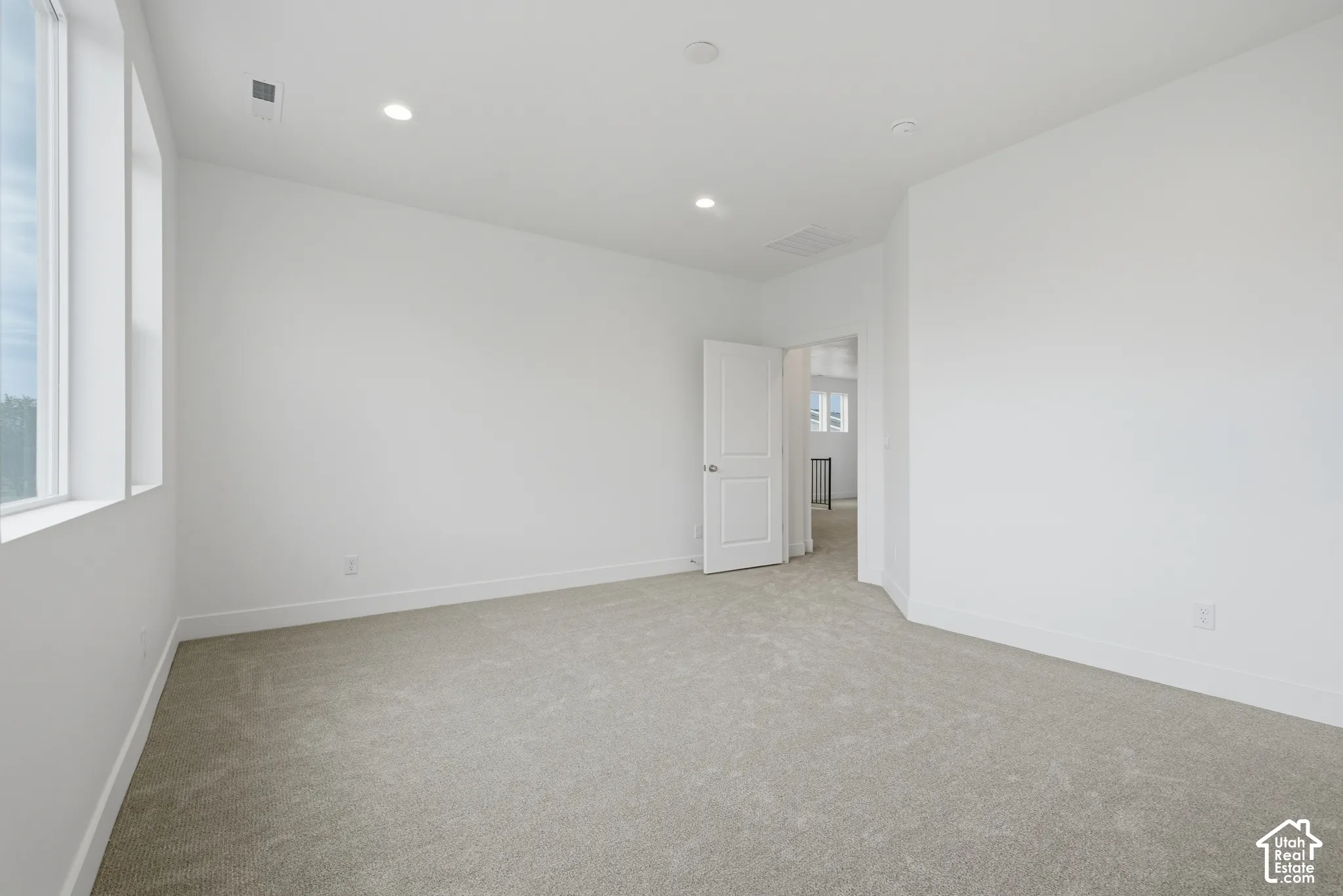 Neutral-toned wall-to-wall carpeting, expansive multi-pane windows, recessed ceiling lighting, and a six-panel interior door
