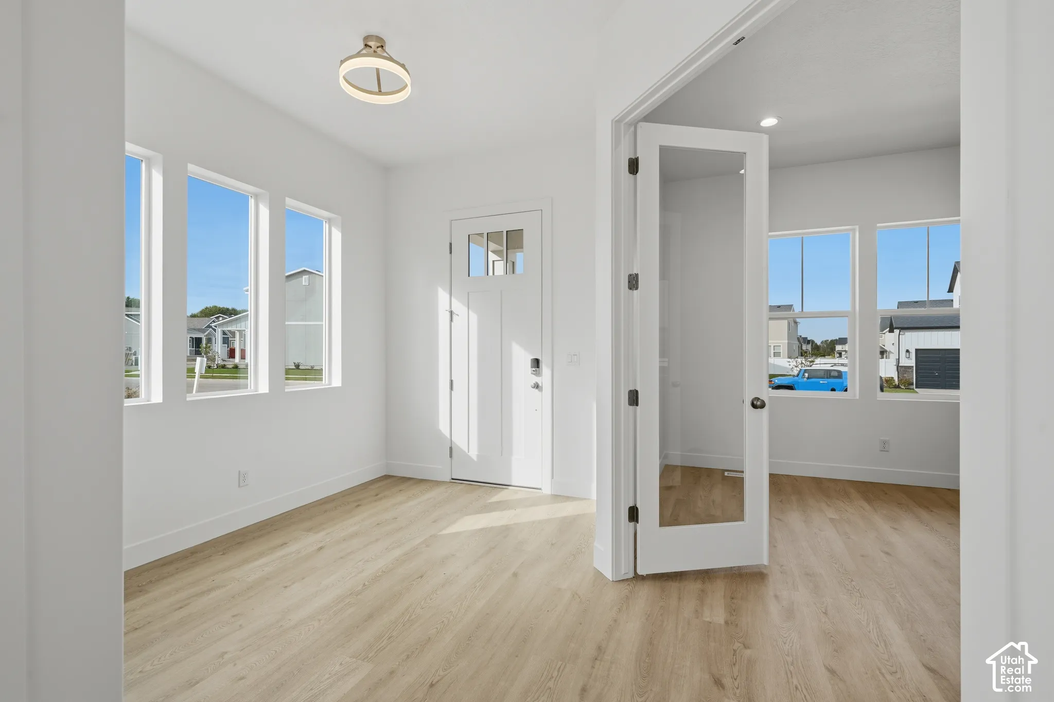 Entryway featuring wood-finish flooring, recessed lighting, a decorative ceiling fixture, multiple windows, and a glass-panel French door