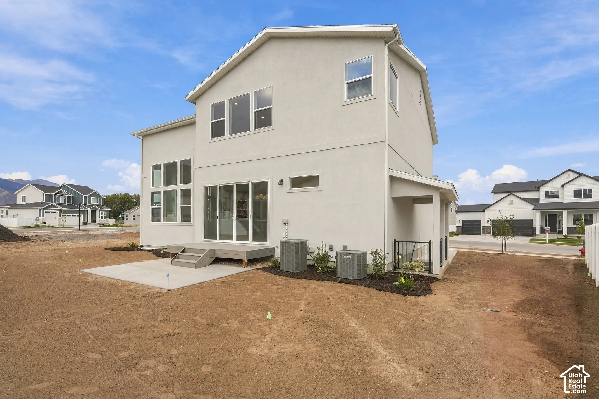 Stucco exterior featuring multi-pane windows, sliding glass doors, a concrete patio, and a covered entry