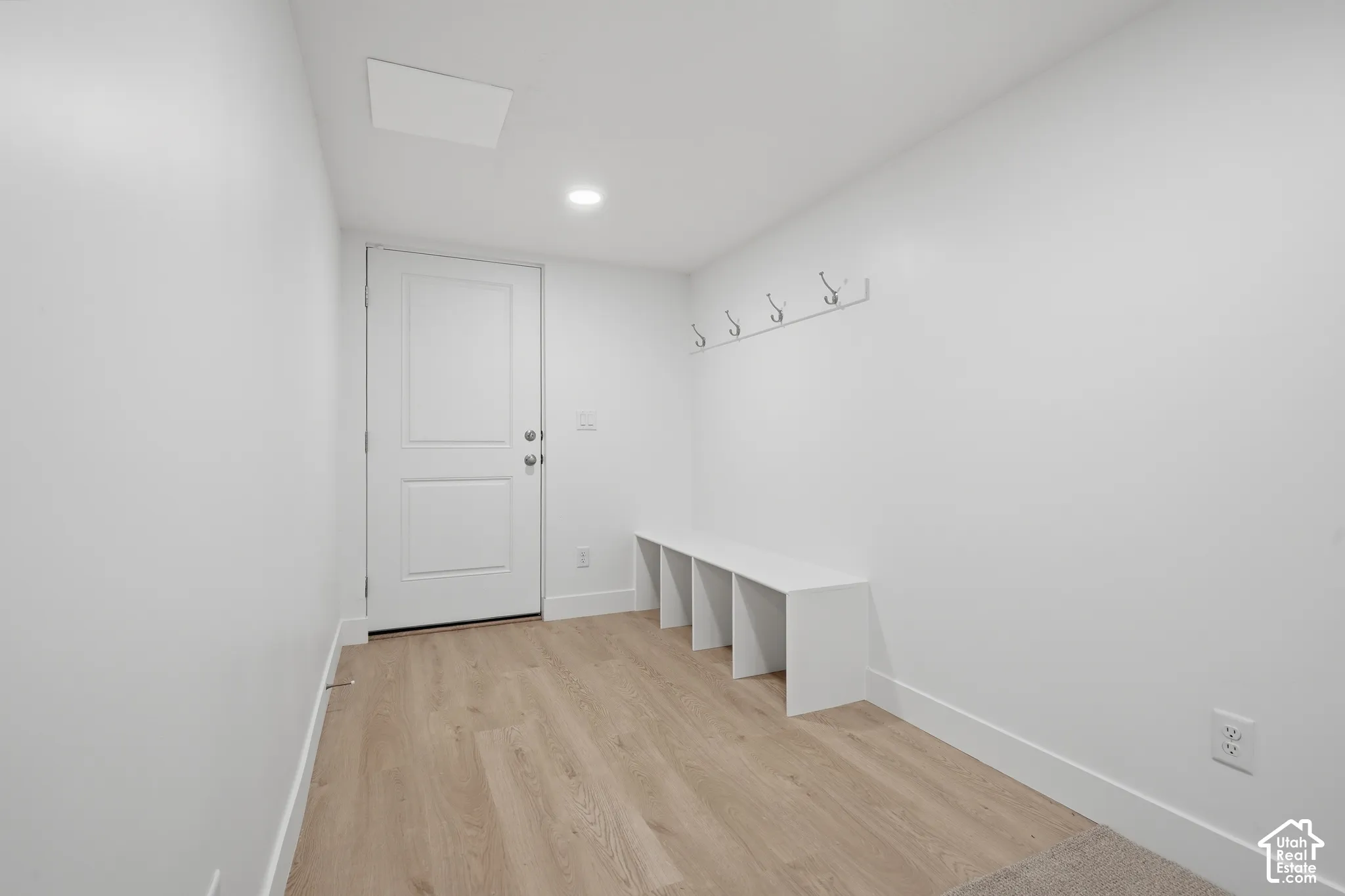 Mudroom area featuring wood-finish flooring, built-in storage cubbies, wall-mounted coat hooks, and recessed lighting