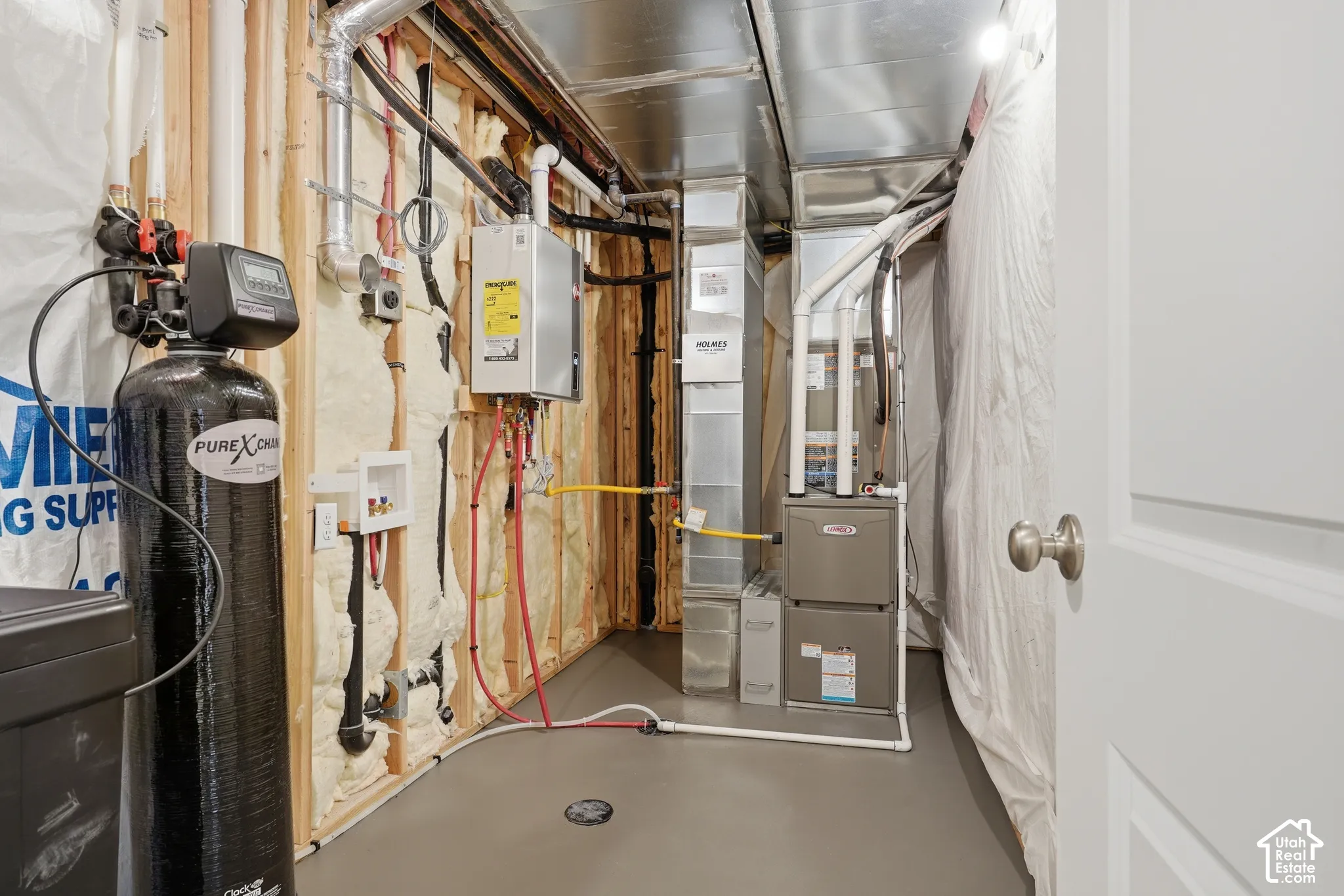 Mechanical room featuring a high-efficiency furnace, tankless water heater, water softening system, and spray foam insulation