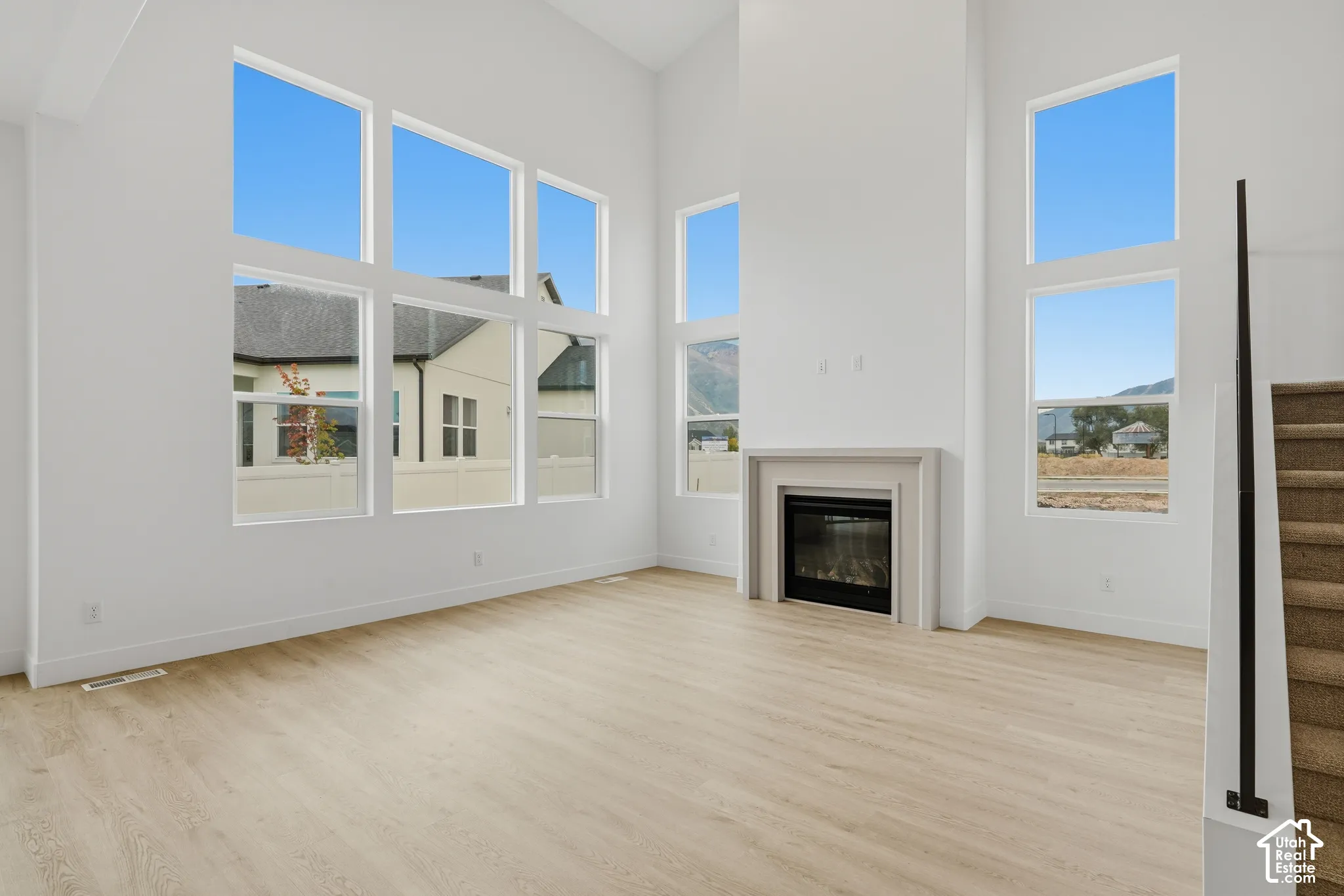 Living area featuring a vaulted ceiling, floor-to-ceiling windows, gas fireplace with a neutral surround, and wood-finish flooring