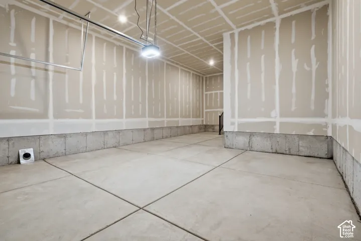 Unfinished garage interior featuring concrete flooring, concrete foundation walls, and taped drywall