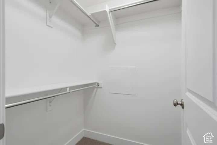 Walk-in closet featuring dual-level metal hanging rods and white built-in shelving