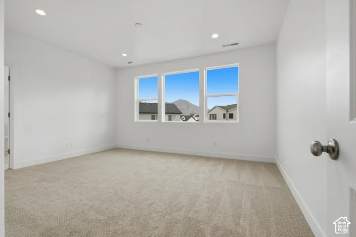 Neutral-toned carpeted flooring, recessed lighting, and triple windows featuring mountain scenery