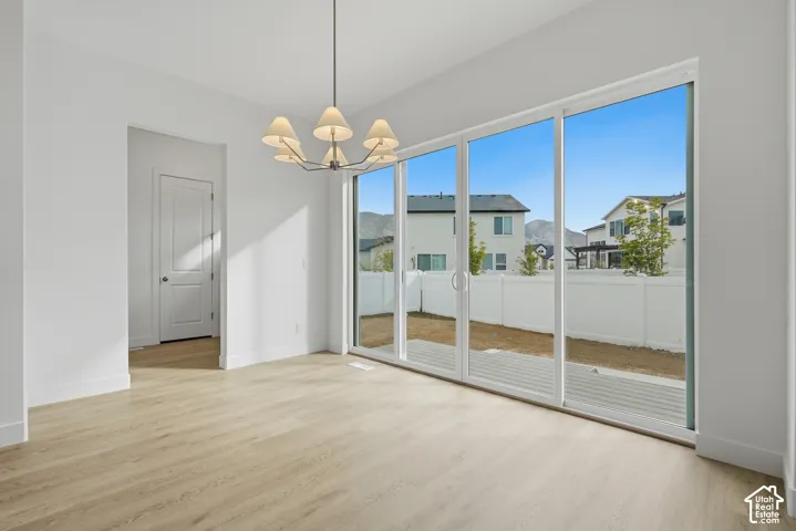 Wood-finish flooring, multi-panel sliding glass doors, metal chandelier with fabric shades, and white interior door