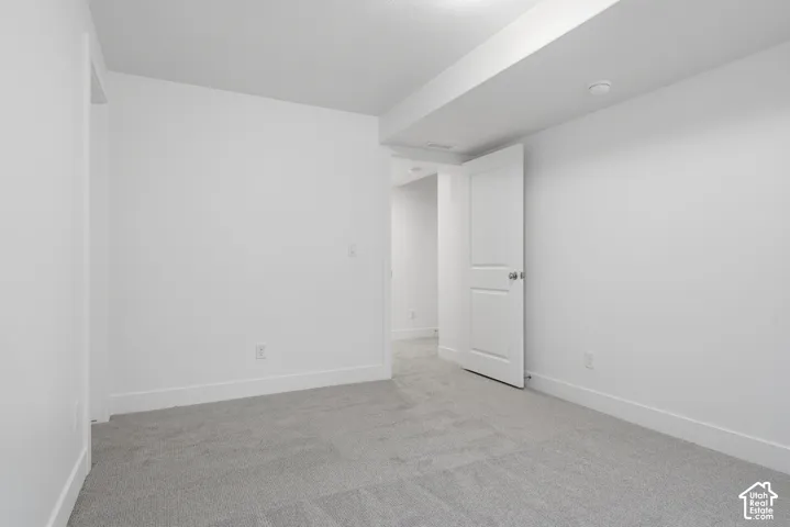 Interior space featuring neutral-toned carpeting, crisp white walls, and a recessed ceiling architectural element