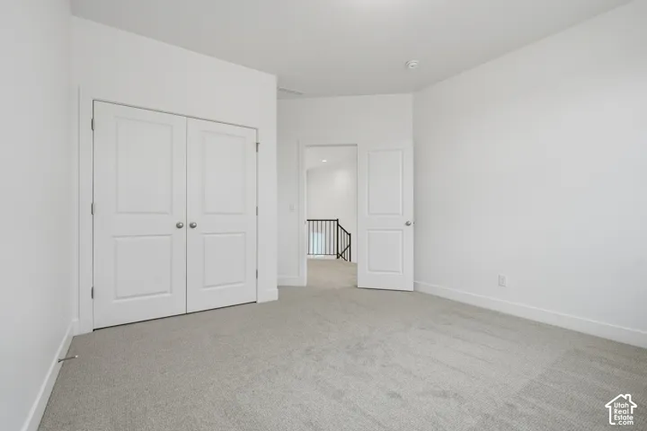 Neutral-toned carpeting, white walls, dual-panel closet doors, and solid-core passage door