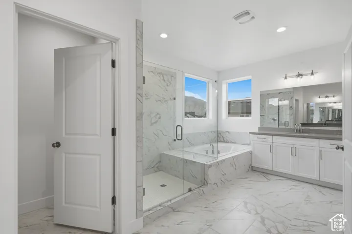 Glass-enclosed shower with stone-finish surround, built-in soaking tub, dual-sink vanity with stone-finish countertop, and stone-finish floor tile