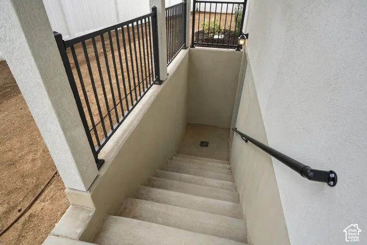 Concrete exterior staircase featuring metal railings, a wall-mounted handrail, and an integrated drainage system