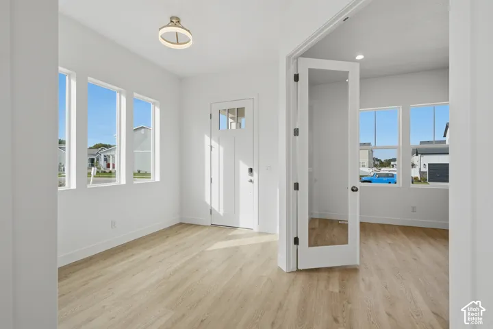 Entryway featuring wood-finish flooring, recessed lighting, a decorative ceiling fixture, multiple windows, and a glass-panel French door